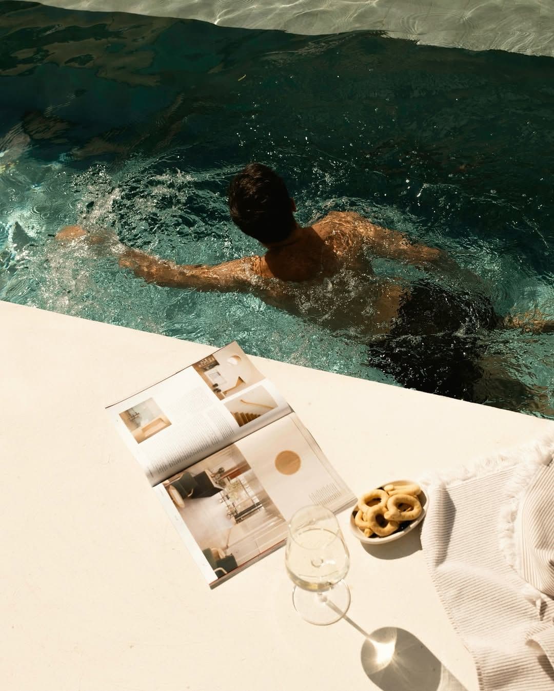 Nageur au bord d'une piscine avec un magazine