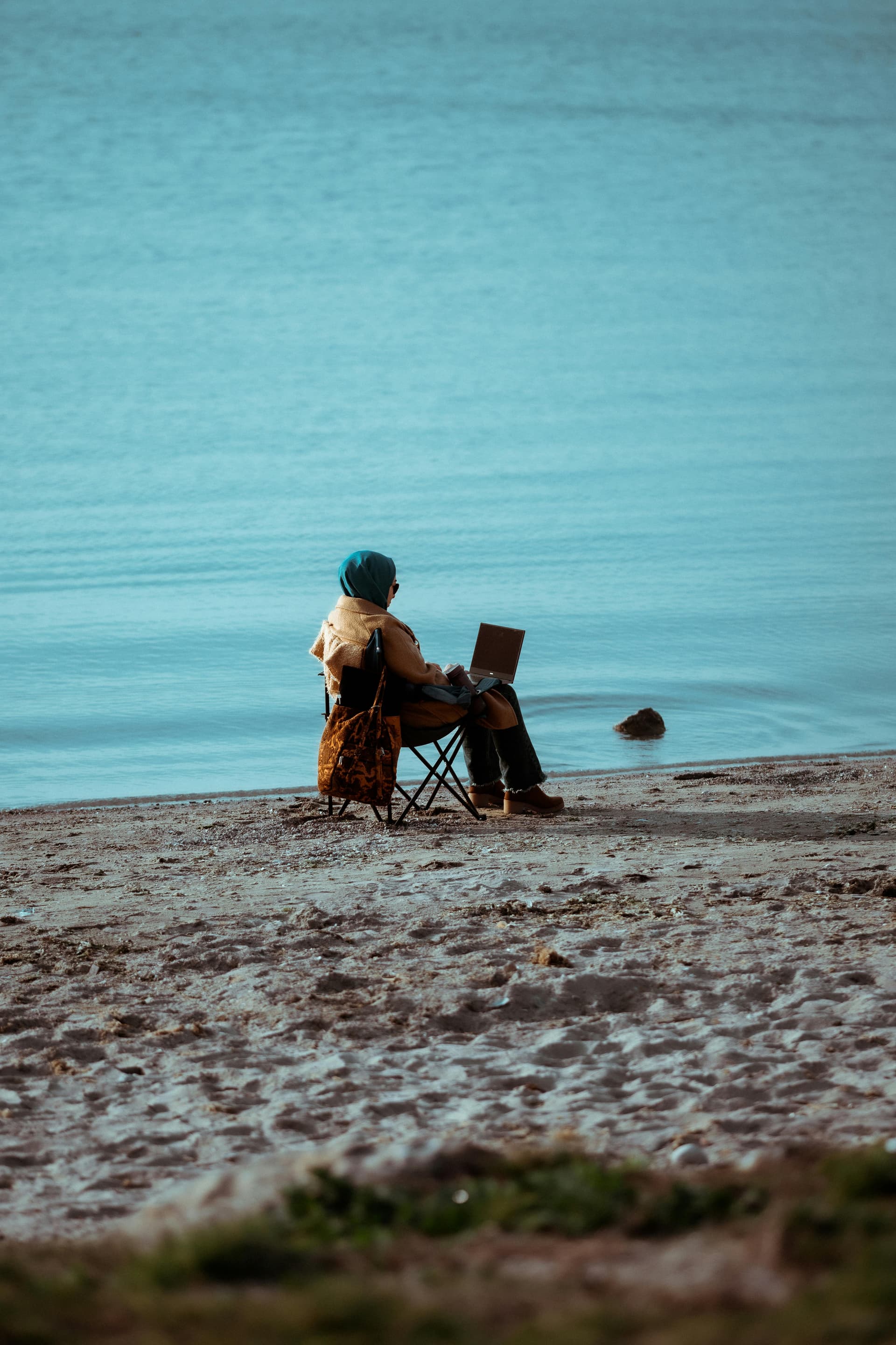 Person sitting on the beach working on a laptop